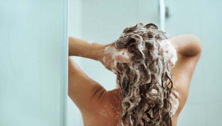Donna in doccia che si fa lo shampoo