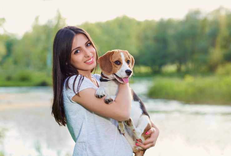 ragazza con cane in braccio sulla spiaggia