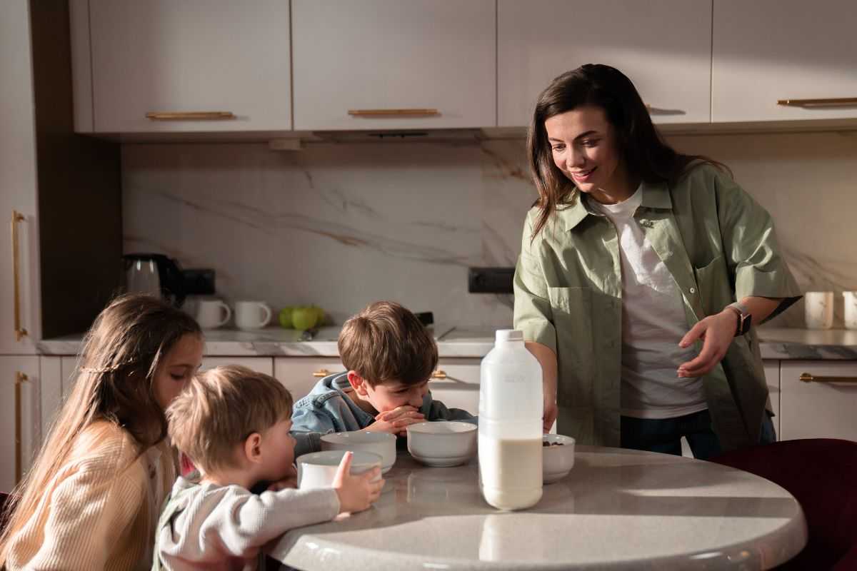 Mamma che versa latte per colazione figli